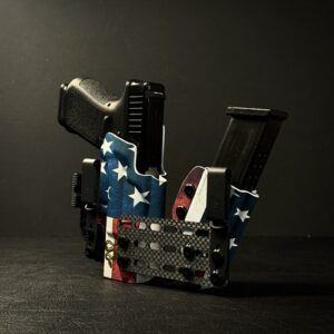 Compact tactical gun holster holding two pistols and magazines, wrapped in American flag fabric, on a dark surface.