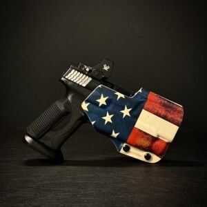 Handgun with a decorative American flag design on the grip, resting on a dark surface.